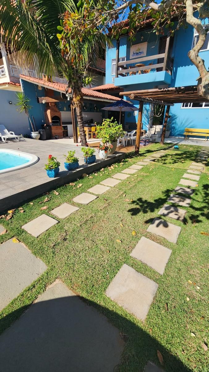 Caminho de pedras no jardim até a casa, com coqueiro e piscina