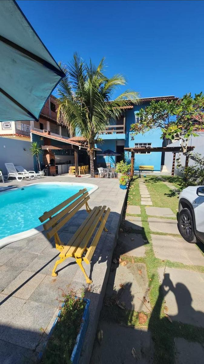 Piscina e bancos amarelos ao lado da casa