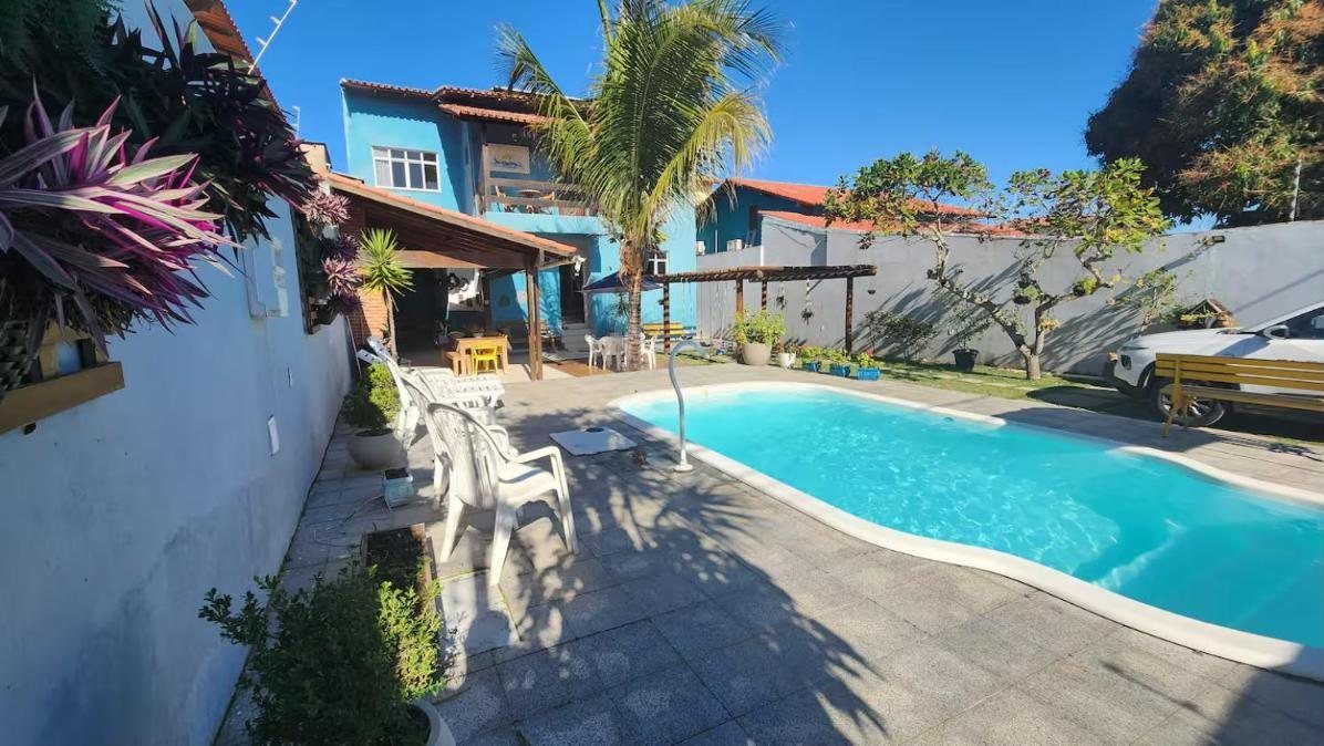 Piscina privativa num dia de sol, com a casa e o coqueiro ao fundo