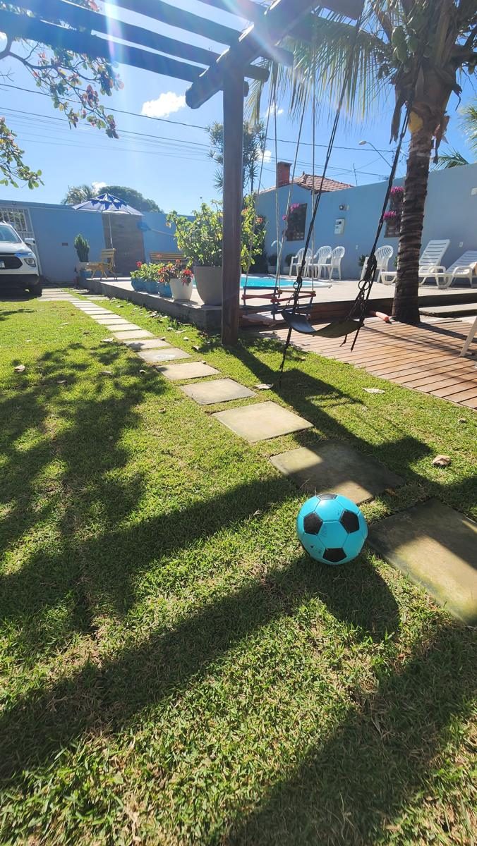 Quintal gramado com bola, balanço no pergolado e piscina ao lado